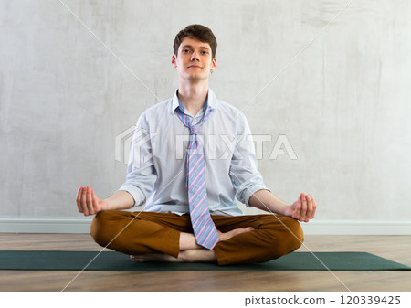 Young businessman doing yoga in office Young businessman doing yoga in office 120339425