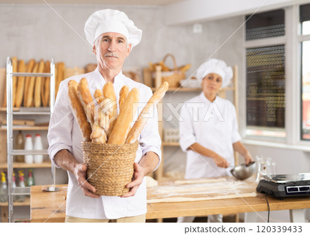 Elderly man with basket of baguettes in bakery 120339433
