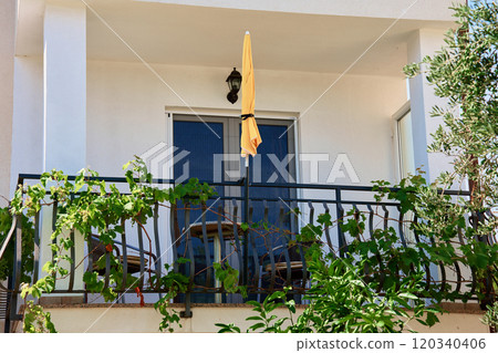 Yellow parasol and grapevine decorating balcony in residential building. Coastal villa at summer day Yellow parasol and grapevine decorating balcony in residential building. Coastal villa at summer day 120340406