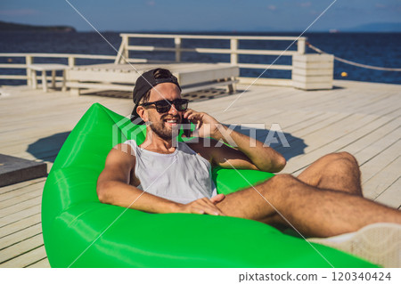 Young man enjoying leisure, lying on the air sofa Lamzac, near the sea Young man enjoying leisure, lying on the air sofa Lamzac, near the sea 120340424