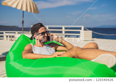 Young man enjoying leisure, lying on the air sofa Lamzac, near the sea Young man enjoying leisure, lying on the air sofa Lamzac, near the sea 120340426