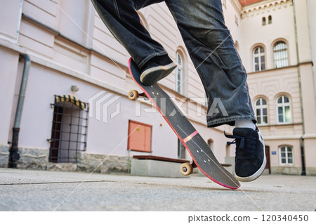 Skateboarder doing ollie trick at urban street. Close up of skater wearing baggy jeans balancing on skateboard. Concept of youth subculture Skateboarder doing ollie trick at urban street. Close up of skater wearing baggy jeans balancing on skateboard. Concept of youth subculture 120340450