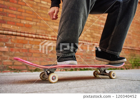 Skateboarder doing trick at urban street. Close up of skater wearing baggy jeans balancing on skateboard. Concept of youth subculture Skateboarder doing trick at urban street. Close up of skater wearing baggy jeans balancing on skateboard. Concept of youth subculture 120340452