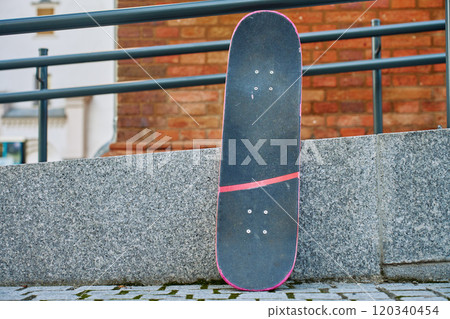 Used scratched pink skateboard against stone wall at city street. Urban sport and youth subculture concept Used scratched pink skateboard against stone wall at city street. Urban sport and youth subculture concept 120340454