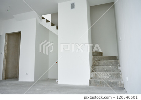 Empty apartment with unfinished concrete staircase and white walls undergoing renovation. Interior of building under construction 120340501