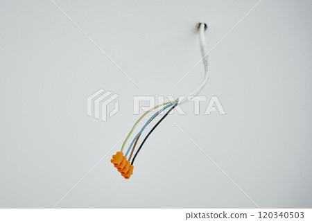 Close-up of electrical wires extending from white wall. Electrical work during apartment renovation. Electricity cable in new apartment Close-up of electrical wires extending from white wall. Electrical work during apartment renovation. Electricity cable in new apartment 120340503