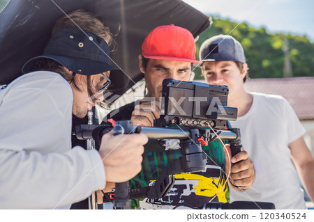 Steadicam operator and his assistant prepare camera and 3-axis stabilizer-gimbal for a commercial shoot Steadicam operator and his assistant prepare camera and 3-axis stabilizer-gimbal for a commercial shoot 120340524