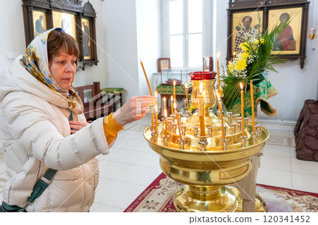 Woman Lighting a Candle in a Russian Orthodox Church Woman Lighting a Candle in a Russian Orthodox Church 120341452