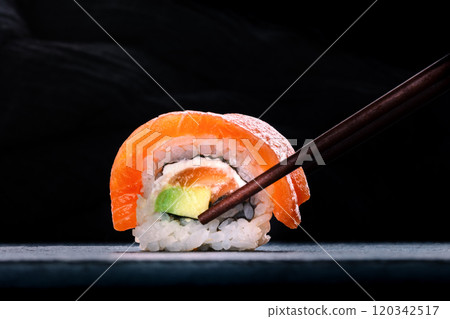 Salmon sushi with avocado and cream cheese, uramaki roll on black Salmon sushi with avocado and cream cheese, uramaki roll on black 120342517