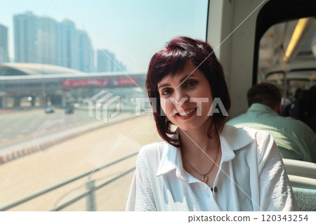 A woman aged 40-44 rides the subway to work, sitting near the window A woman aged 40-44 rides the subway to work, sitting near the window 120343254