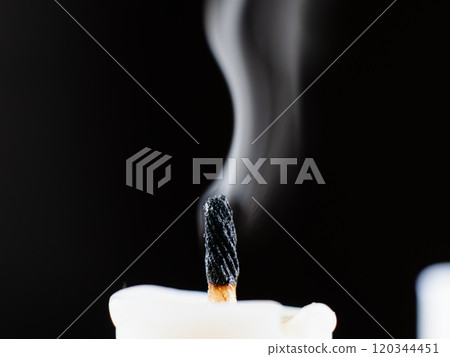 Candle wick smoking after being extinguished in darkness 120344451