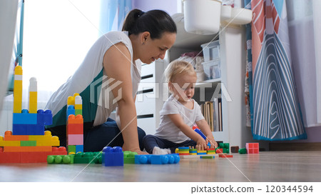 Mother and baby enjoy playing with a colorful educational wooden toy in their cozy nursery 120344594