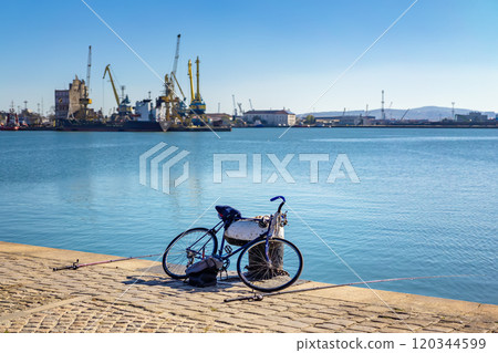 Bicycle and fishing rods lying by the tranquil waterfront at the harbor Bicycle and fishing rods lying by the tranquil waterfront at the harbor 120344599