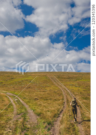 Young Woman Tourist Walking Up Mountain Hill Young Woman Tourist Walking Up Mountain Hill 120345396