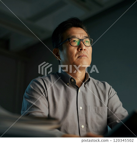 A male employee in his 50s working late nights at a black company 120345502