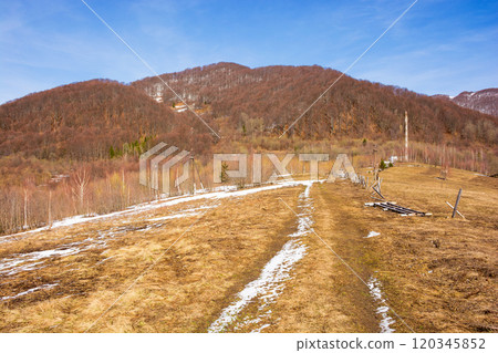 season change in carpathian mountains. seasonal transition. sunny day in spring. leafless forest and snow on the hill. nature landscape 120345852