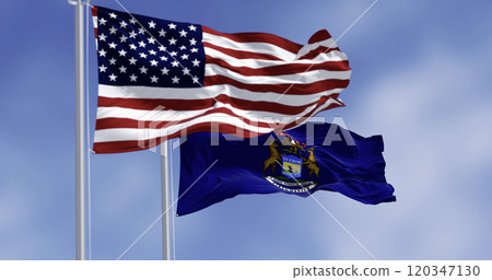 Michigan state flag and national american flag waving in the wind on a clear day 120347130