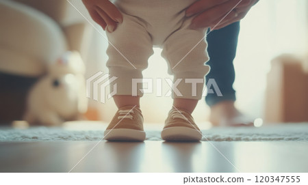 Adorable baby taking first steps with parental support 120347555