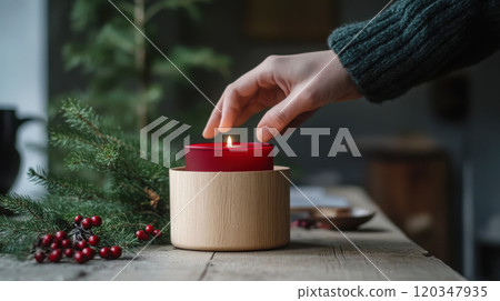 Minimalist holiday decor: hand placing a red candle in wooden holder for cozy ambiance 120347935