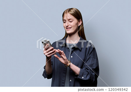 Young beautiful woman using smartphone on grey studio background Young beautiful woman using smartphone on grey studio background 120349342