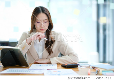 Businesswoman feeling stressed while analyzing data at her desk 120349347