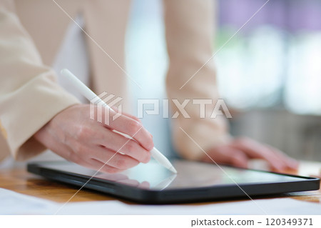 Close-up of hand signing electronic documents on a tablet with a digital pen for online workflows 120349371