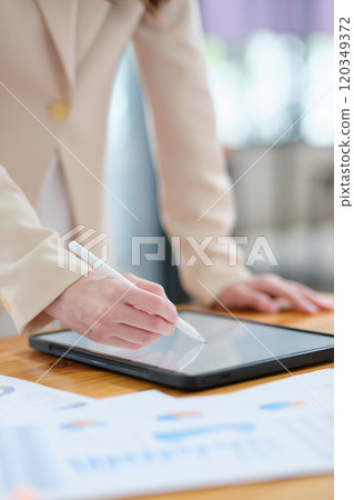 Close-up of hand signing electronic documents on a tablet with a digital pen for online workflows 120349372