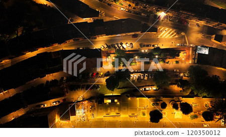 Aerial view of a small town at night showing street lights illuminating buildings and parked cars 120350012