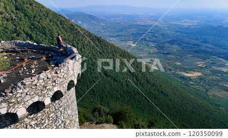 A solitary figure enjoys the breathtaking view from an ancient stone tower perched on a mountain during a clear day in the countryside A solitary figure enjoys the breathtaking view from an ancient stone tower perched on a mountain during a clear day in the countryside 120350099