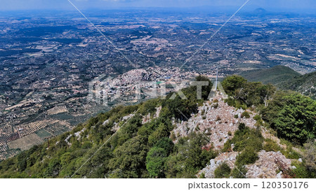 Standing on mountain top overlooking green valley with town and farmland Standing on mountain top overlooking green valley with town and farmland 120350176