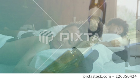 Image of essential oil bottles over diverse couple having hot stones massage Image of essential oil bottles over diverse couple having hot stones massage 120350424