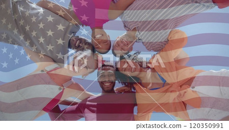 Image of american flag over below view of happy diverse friends embracing in the sun 120350991
