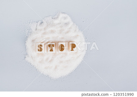 The word stop on pieces of refined sugar on granulated sugar on a blue background, top view The word stop on pieces of refined sugar on granulated sugar on a blue background, top view 120351990
