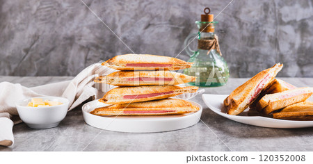 Grilled triangle sandwiches with cheese and sausage on a plate on a table web banner Grilled triangle sandwiches with cheese and sausage on a plate on a table web banner 120352008