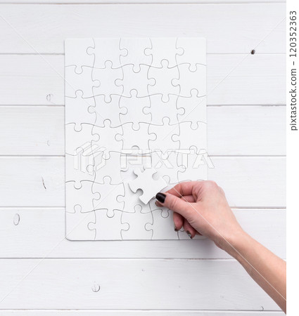 hand holding a piece of white uncompleted puzzle hand holding a piece of white uncompleted puzzle 120352363