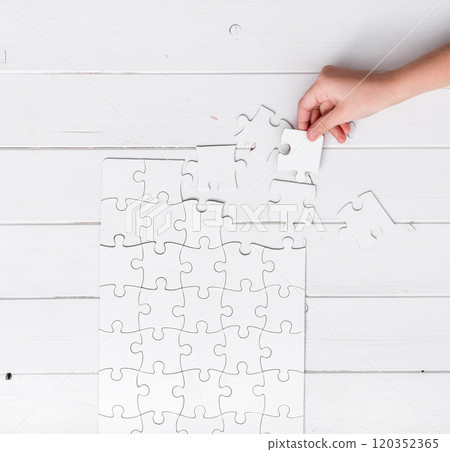 hand holding a piece of white uncompleted puzzle hand holding a piece of white uncompleted puzzle 120352365