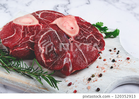 knuckle on the bone, raw meat for ossobuco, on a wooden chopping board, with a sprig of rosemary, and spices, top view, no people, knuckle on the bone, raw meat for ossobuco, on a wooden chopping board, with a sprig of rosemary, and spices, top view, no people, 120352913