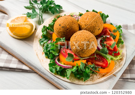 Tortillas, wrapped falafel balls, with fresh vegetables, vegetarian healthy food, on a wooden white background, no people, selective focus. 120352980