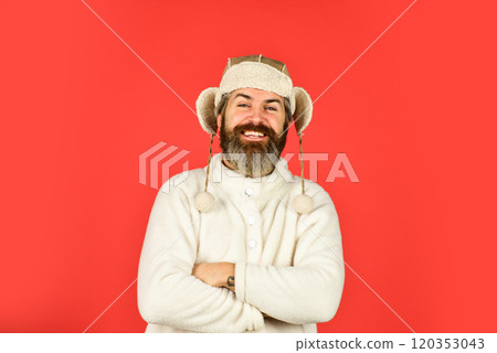 Winter fashion concept. Warm hat for cold weather. Sheep fur. Bearded funny hipster. Perfect accessory. Bearded man wear hat with ear flaps red background. Soft furry accessory. Caring fur garments 120353043