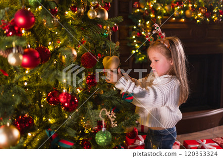 Merry Christmas Xmas holiday. Little girl decorating Christmas tree on Christmas eve at home. Young kid near classical Christmas tree with winter decorations ornaments. Time for celebration Christmas Merry Christmas Xmas holiday. Little girl decorating Christmas tree on Christmas eve at home. Young kid near classical Christmas tree with winter decorations ornaments. Time for celebration Christmas 120353324