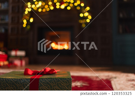 Green gift box in classical Christmas decorated interior living room library with fireplace. Christmas gift near fir tree on Christmas eve. Modern classic style interior design apartment. Christmas Green gift box in classical Christmas decorated interior living room library with fireplace. Christmas gift near fir tree on Christmas eve. Modern classic style interior design apartment. Christmas 120353325