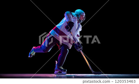 Side view dynamic image of man, hockey player in motion with stick, training, playing intense game against black studio background in neon light Side view dynamic image of man, hockey player in motion with stick, training, playing intense game against black studio background in neon light 120353463