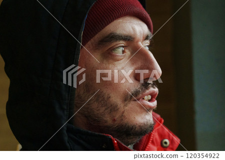 A man with a focused expression is engaged in deep thought, enveloped in a cozy red jacket and beanie A man with a focused expression is engaged in deep thought, enveloped in a cozy red jacket and beanie 120354922