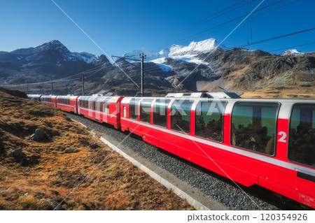 Red train is moving along railway in swiss alps mountain. Autumn 120354926