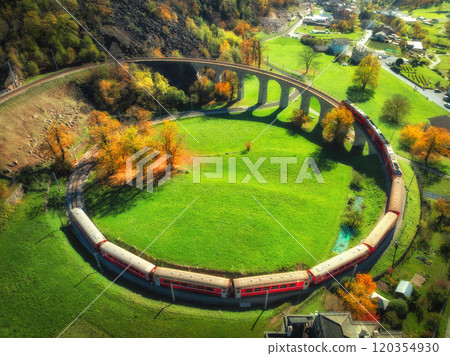 Aerial view of red train on Kreisviadukt Brusio in mountains 120354930