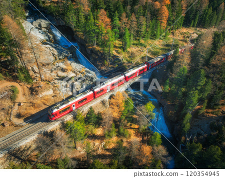 Aerial view of red passenger train on bridge over a waterfall 120354945