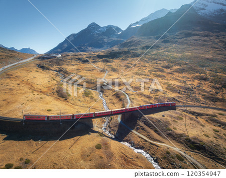 Aerial view of red train is moving in the swiss alps valley Aerial view of red train is moving in the swiss alps valley 120354947