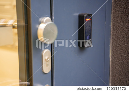 Close up view of door with electric lock with reader of entry system mounted on a house wall 120355570