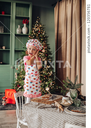 a girl child in the kitchen with a Christmas tree a girl child in the kitchen with a Christmas tree 120356781