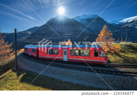 Red electric passenger train is moving on railway in swiss alps Red electric passenger train is moving on railway in swiss alps 120356877